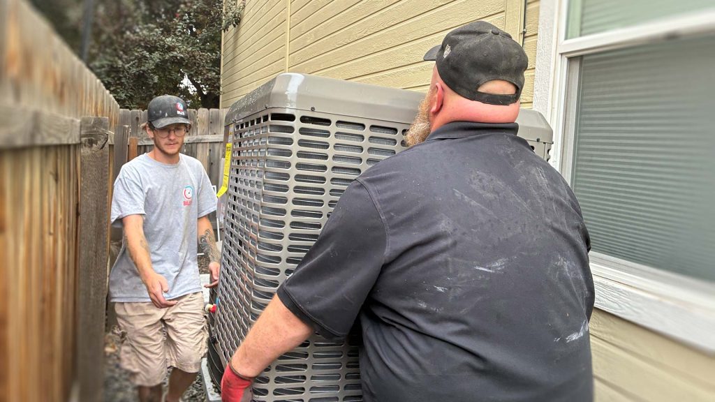 Technicians carrying new A/C unit