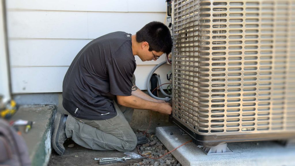 Technician connecting a heat pump to a house